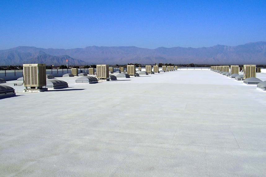 On-roof panoramic view across a vast SWD Urethane spray foam roof lined with HVAC evaporative coolers and skylights, mountains on the horizon.