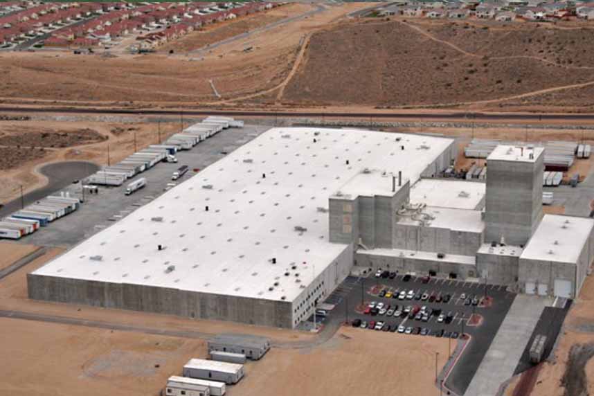 Aerial shot of an expansive manufacturing facility with tractor-trailers and a continuous SWD Urethane spray foam roof across multiple bays.