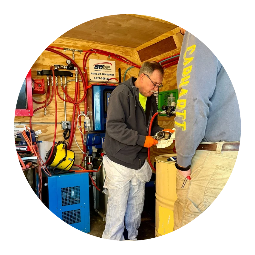 Technician in workshop fills container using pumping equipment surrounded by tools and machinery