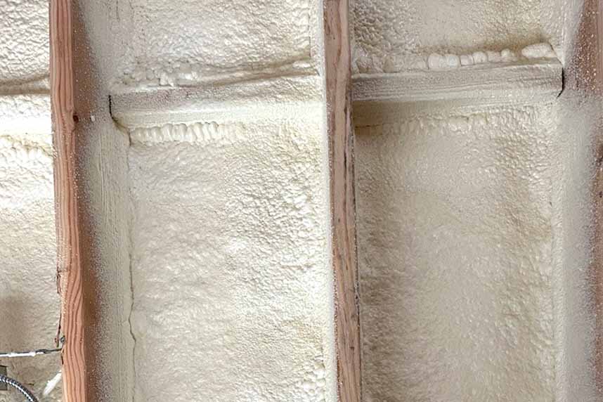 Close-up of wall stud cavity uniformly coated with Quik-Shield® Goblin spray foam, showing smooth texture and airtight seal.