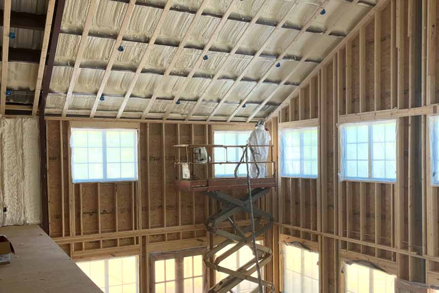 Wide interior shot of scissor-lift crew applying Quik-Shield® Goblin spray foam to high vaulted ceiling in new-build shell.