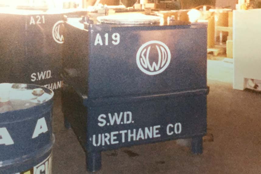 Close-up of dark-blue SWD Urethane day-tanks labeled A19/A21 inside the original factory.