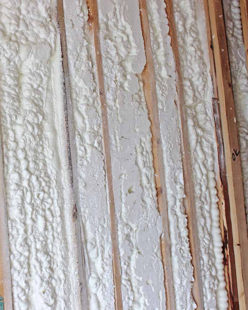 Close-up of spray foam insulation applied between wall studs during an SWD Urethane installation project.